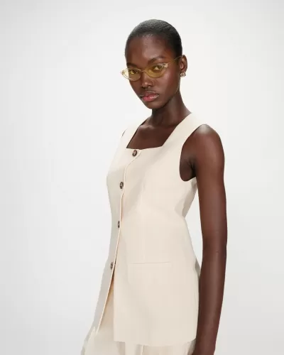 Blusa bege claro com riscas finas e botões castanhos usada por mulher com óculos amarelos