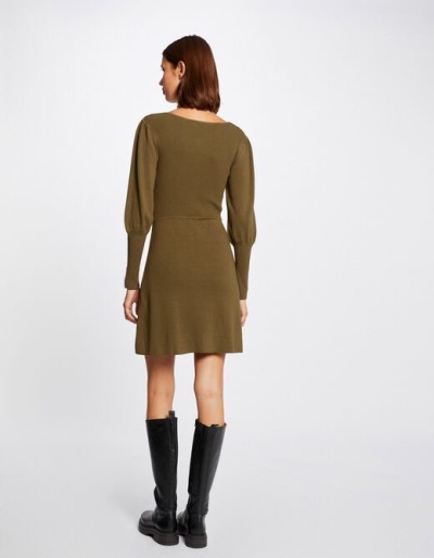 Vestido curto de malha verde-oliva com mangas bufantes e botas pretas, visto de costas