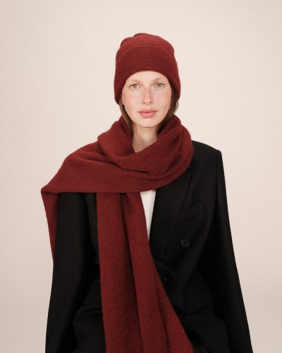 Mulher com gorro e cachecol bordô e casaco preto