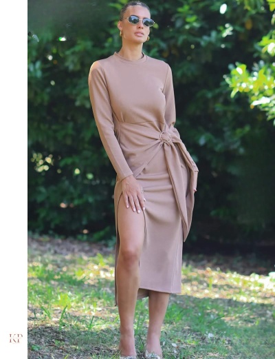 Vestido comprido castanho claro com nó decorativo e racha lateral usado por mulher ao ar livre