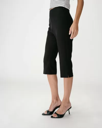 Calças capri pretas femininas com pequena abertura na bainha e sandálias pretas de salto alto