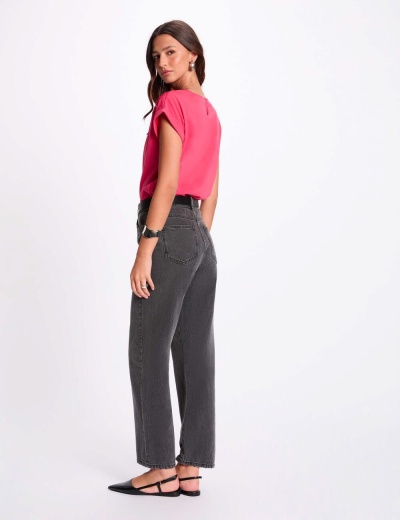 Mulher com calças de ganga cinzentas escuras e t-shirt rosa em fundo branco
