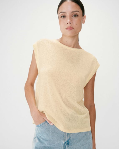 Mulher com t-shirt bege clara sem mangas e jeans azul claro