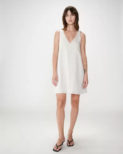 Vestido bege claro de linho ou algodão com alça de nó e sandálias pretas