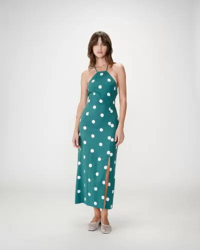 Mulher com vestido verde de bolinhas brancas e decote halter