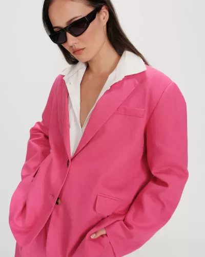 Mulher com blazer rosa e óculos de sol pretos.