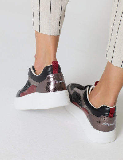 Tênis desportivos com sola branca e detalhes em cores escuras usados por uma pessoa