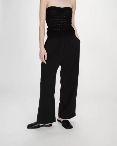 Pessoa com calças e blusa pretas e sapatos pretos em fundo branco