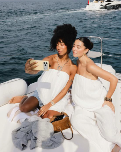 Duas mulheres em roupas brancas em barco com mar ao fundo.