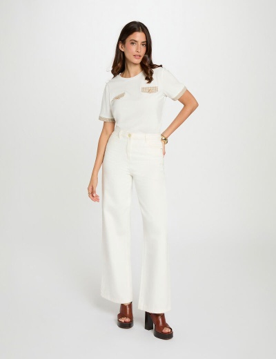 Mulher com t-shirt branca e calças brancas largas com sapatos castanhos de salto alto