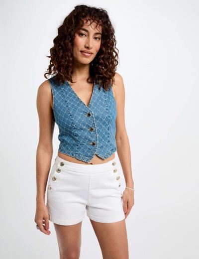 Mulher com colete azul de ganga e calções brancos, em fundo branco.