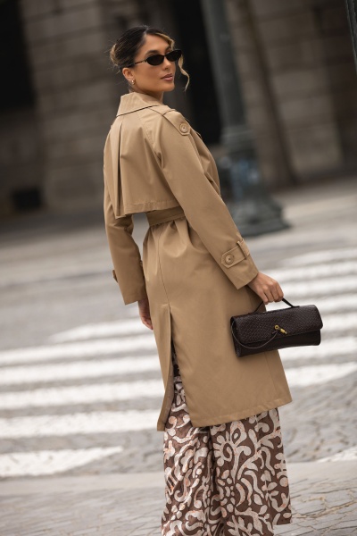 Mulher com gabardina bege e carteira preta numa rua urbana