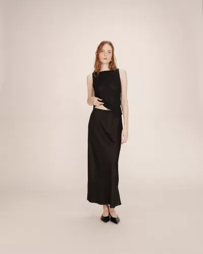 mulher com top preto e saia preta longa em fundo bege