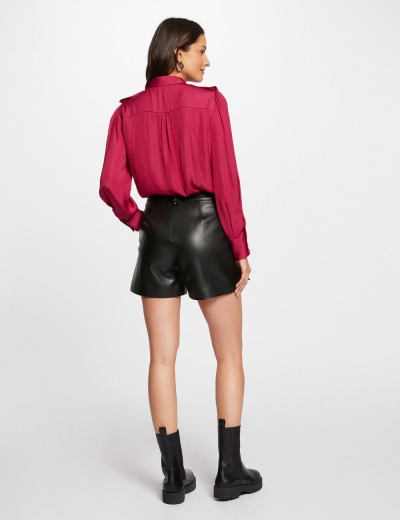 Mulher de costas com blusa rosa, calções pretos em couro e botins pretos