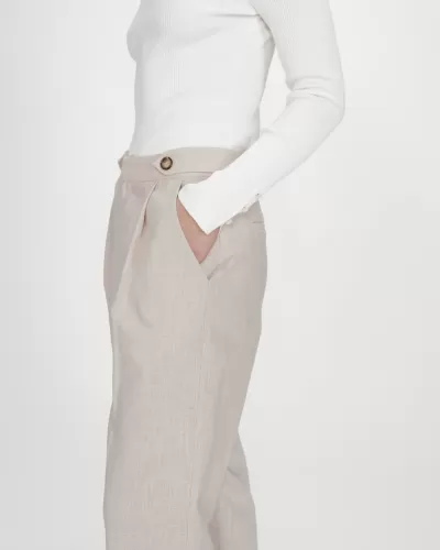 Calças bege claro com bolso e cinto, usada com camisola branca canelada