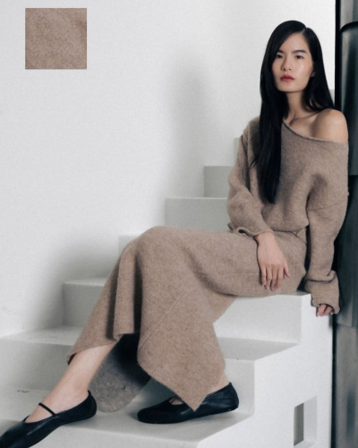 Mulher veste vestido castanho claro em malha com textura suave sentada escadaria branca