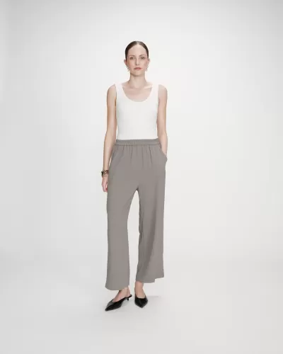 Mulher vestindo top branco e calças largas cinza com sapatos pretos