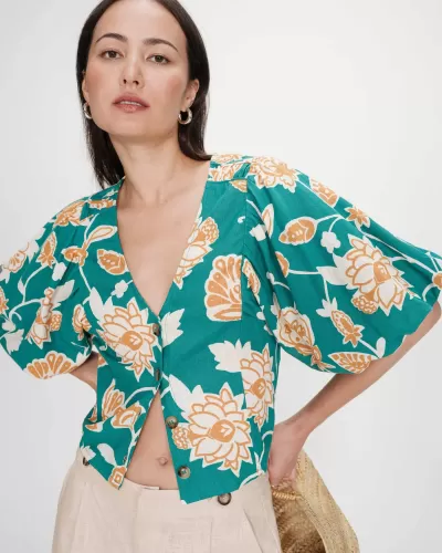 Blusa floral verde com botões e mangas bufantes usada por mulher.