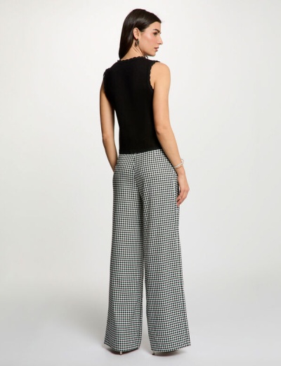 Mulher vestindo top preto sem mangas e calças xadrez em fundo branco
