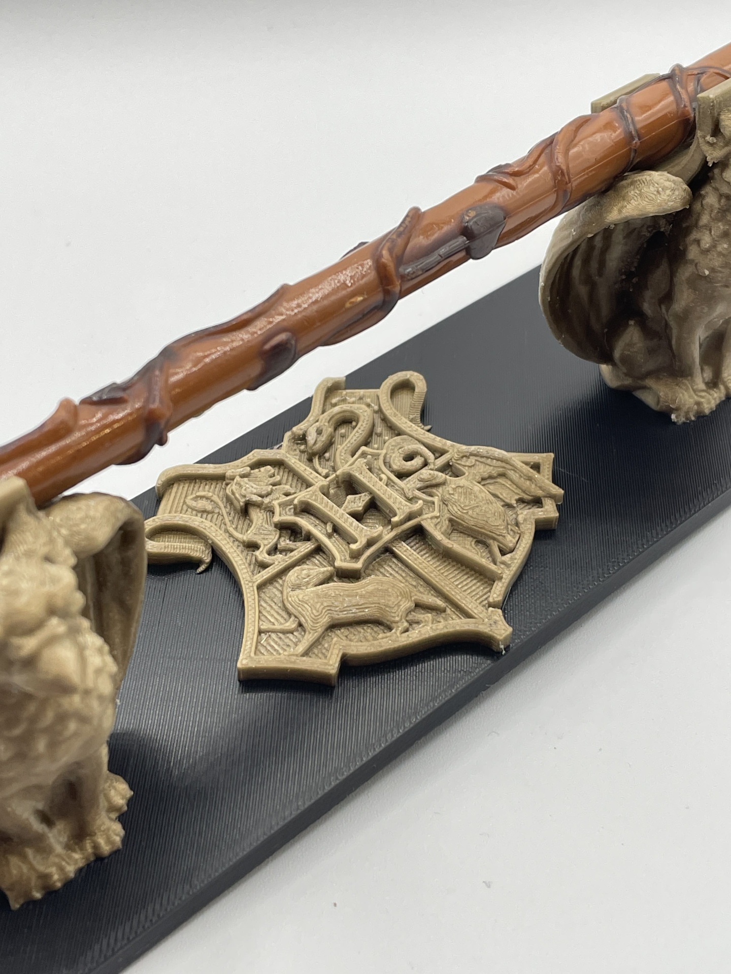 Serviço de Impressão 3D Personalizada – Transforme seus Modelos Digitais em Realidade Miniatura da varinha de Harry Potter com brasão de Hogwarts e caveiras em suporte preto