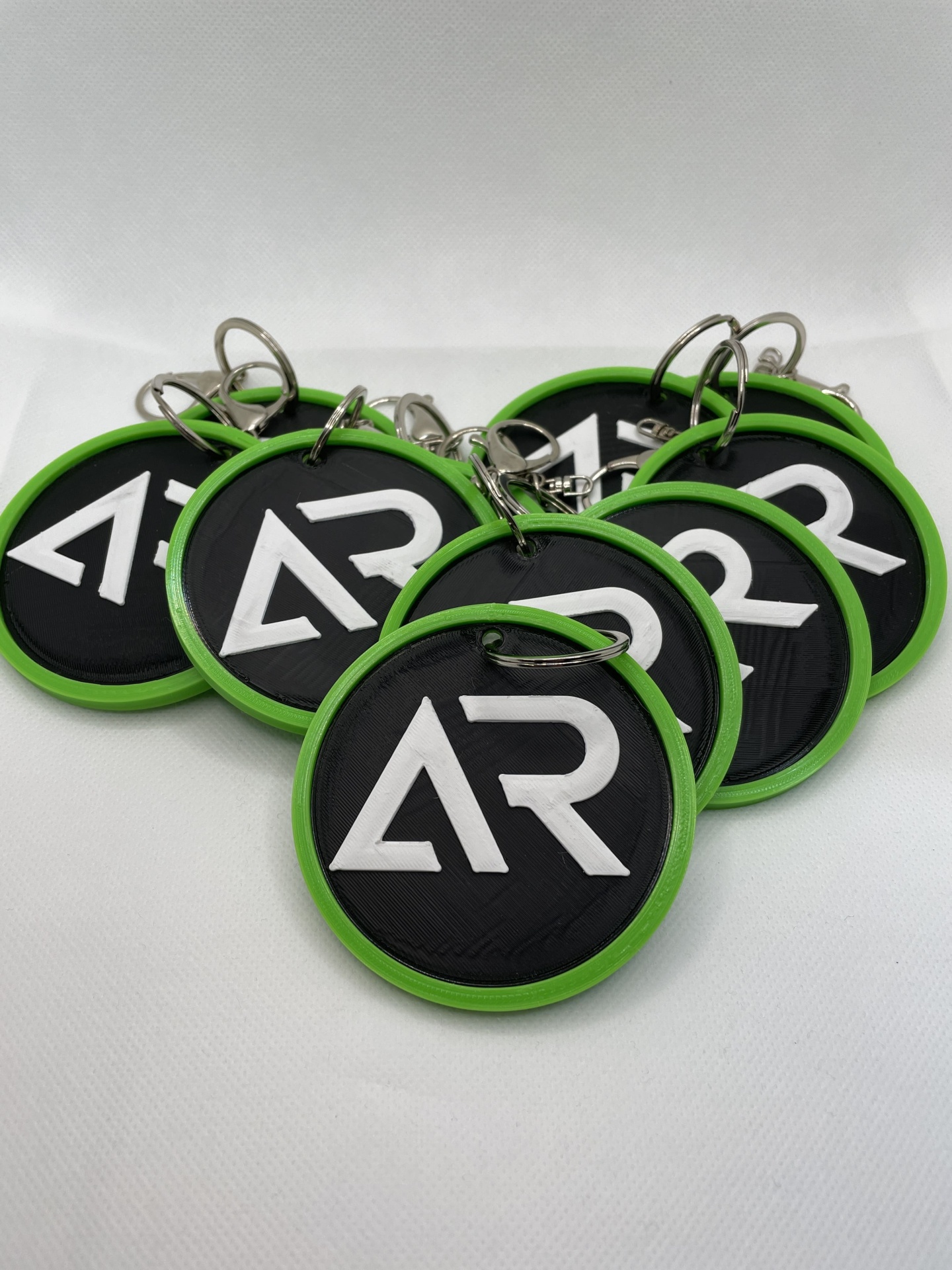 Serviço de Impressão 3D Personalizada – Transforme seus Modelos Digitais em Realidade Porta-chaves redondos com borda verde e logótipo AR branco sobre fundo preto