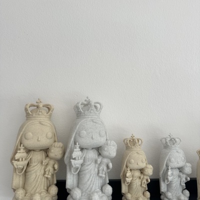 Estatuetas decorativas femininas com coroas em tons bege e cinza numa prateleira preta