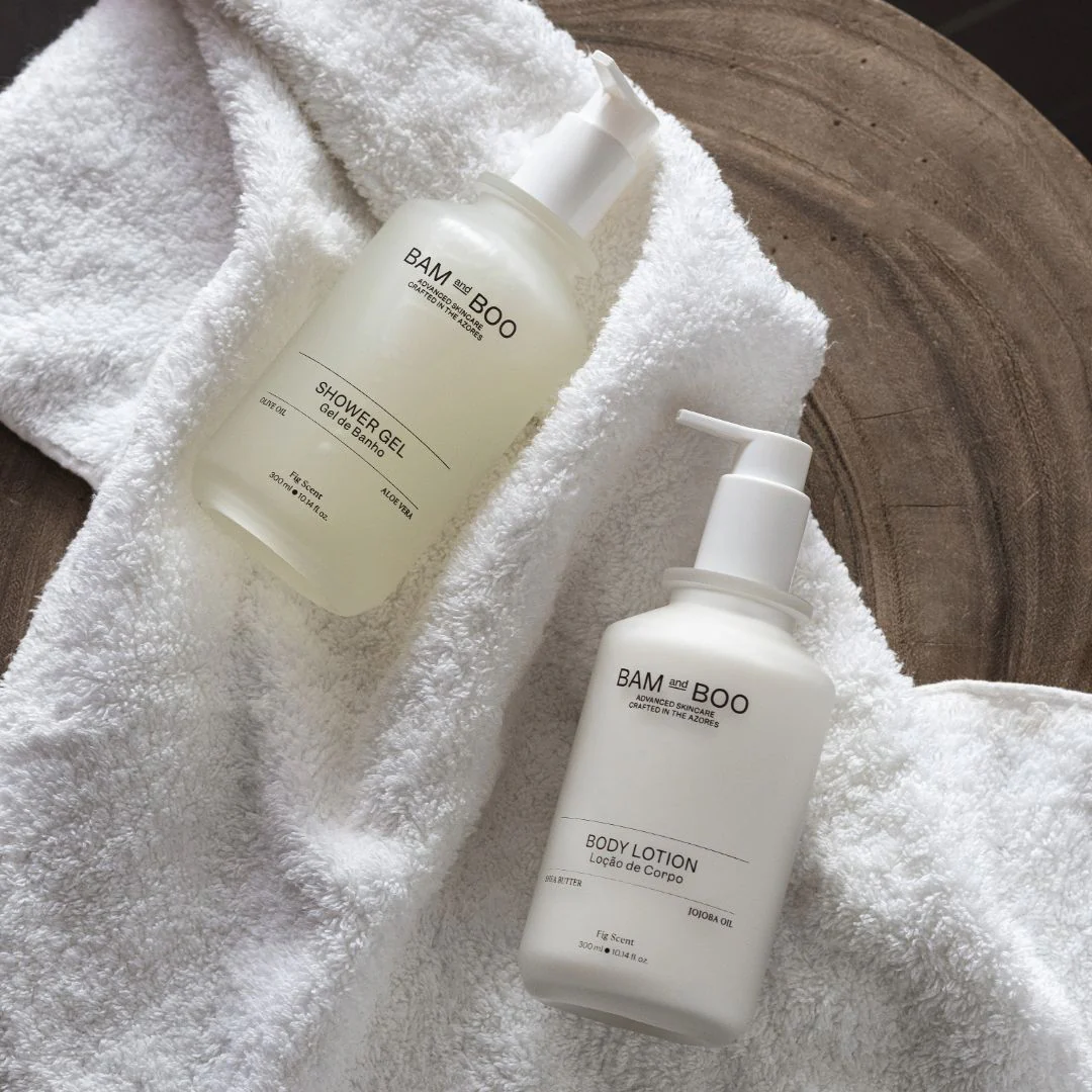Frascos de gel de banho e loção corporal BAM and BOO sobre toalha branca felpuda