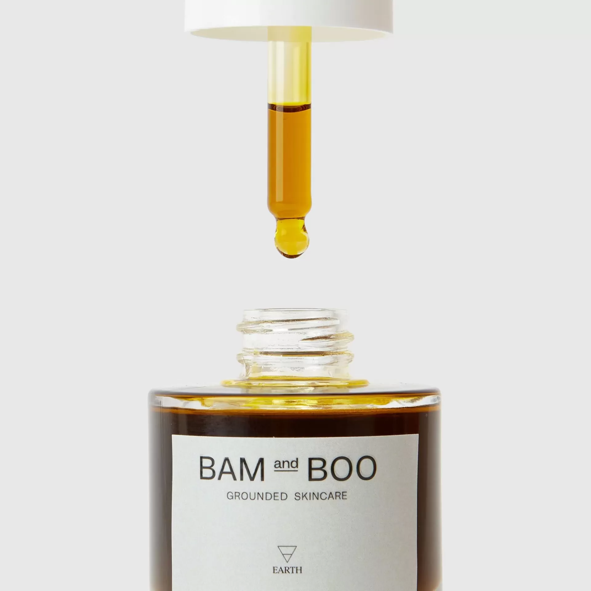 Conta-gotas com líquido amarelo sobre frasco de vidro castanho com rótulo BAM and BOO