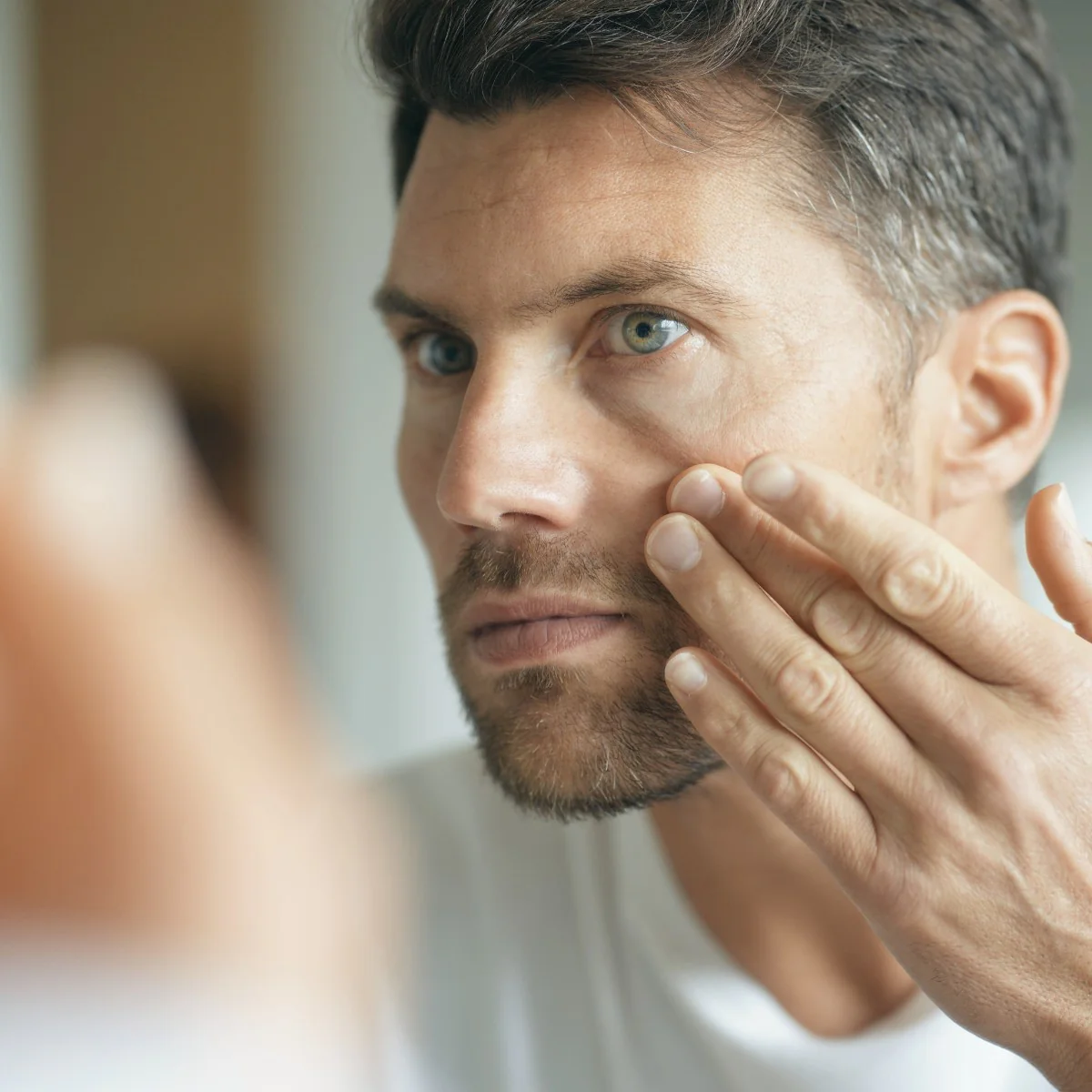 Homem a cuidar da pele do rosto com dedo em ambiente interior