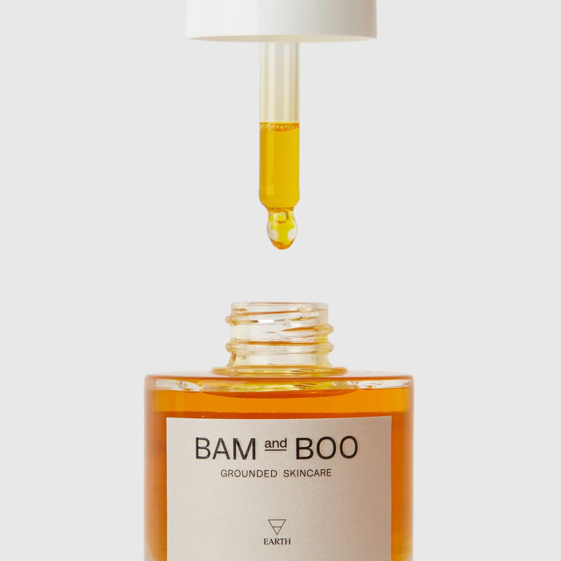 Frasco de vidro com líquido amarelo alaranjado e conta-gotas com tampa branca