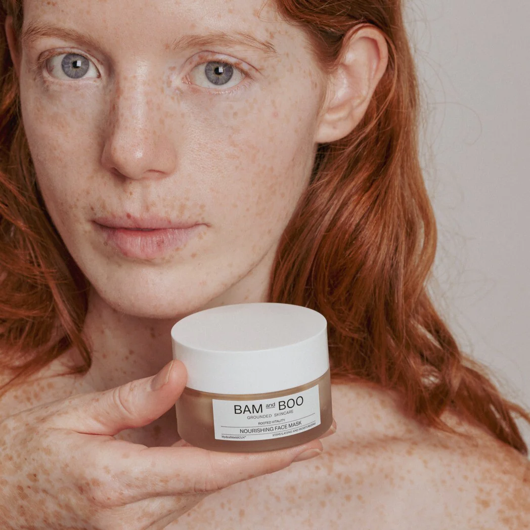Frasco de máscara facial nutriente BAM and BOO segurado por mulher ruiva com sardas