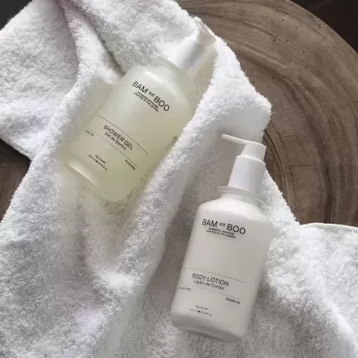 Frascos de gel de banho e loção corporal BAM and BOO sobre toalha branca felpuda