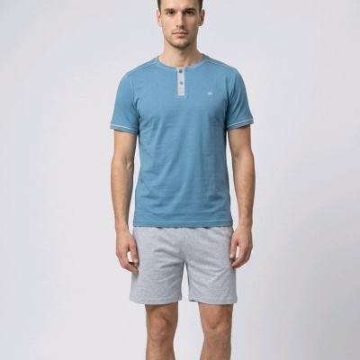 Homem com t-shirt azul e calções cinzentos em fundo branco