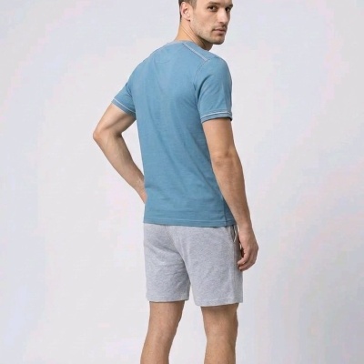 Homem de costas a usar t-shirt azul e calções cinzentos