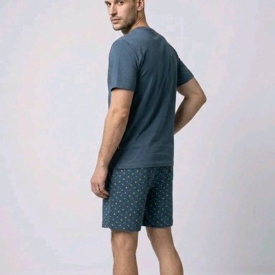 Homem de costas com t-shirt azul escura e calções azuis com padrão floral pequeno.