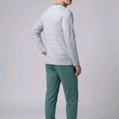 Pijama masculino com camisola cinza riscada e calças verdes, chinelos cinza, modelo de costas em fundo neutro.