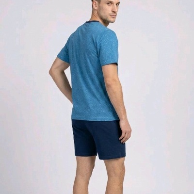 Homem com t-shirt azul e calções azul escuro em fundo cinzento claro