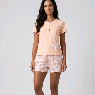 Mulher com pijama cor de pêssego com bolsos estampados e calções com padrão de folhas.