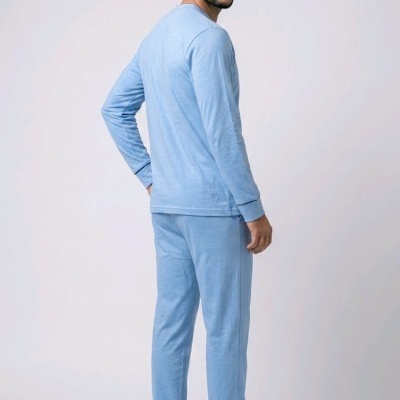 Homem com pijama azul claro e calçado preto em fundo branco