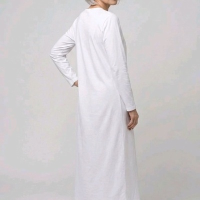 mulher de cabelos grisalhos vestindo vestido branco longo de manga comprida e ténis creme