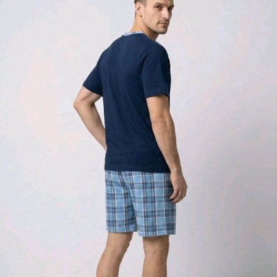 Homem de costas com t-shirt azul escuro e calções azuis aos quadrados.