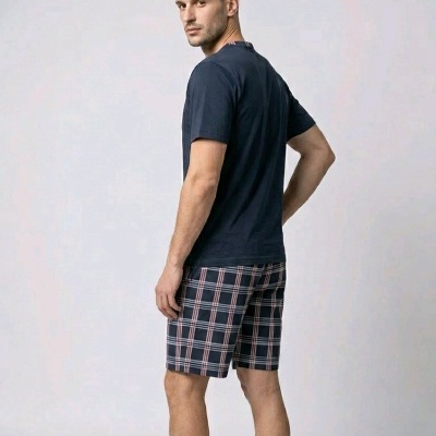 Homem de costas com t-shirt azul escura e calções aos quadrados azul e rosa