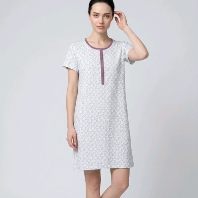 Mulher com vestido curto branco com padrão cinza e detalhes roxos, fundo branco.