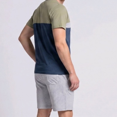 Homem de costas vestindo t-shirt bicolor verde-oliva e azul escuro e calções cinza com padrão de riscas finas.