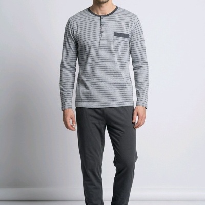 Homem a usar pijama cinzento com riscas horizontais pretas, calças e chinelos cinzentos, fundo branco