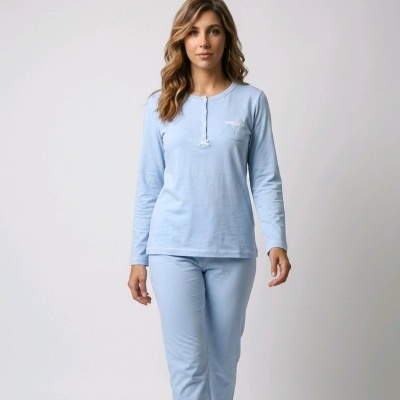 Mulher a usar conjunto de pijama azul claro em cenário neutro