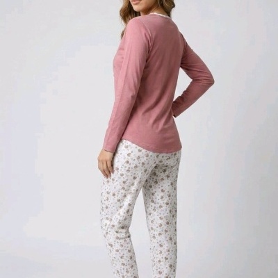 Modelo de mulher a vestir conjunto de pijama rosa e calças brancas com padrão floral