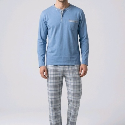Homem com pijama azul claro e calças xadrez cinzentas com chinelos pretos