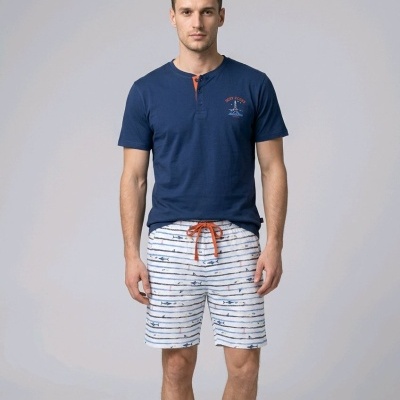 Homem com t-shirt azul escuro e calções brancos com padrão listrado azul e desenhos de peixes.