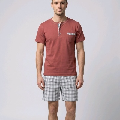 Homem com pijama t-shirt terracota e calções xadrez cinzentos.